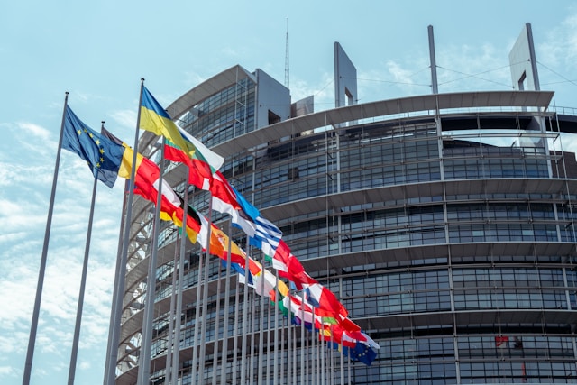Le drapeau ukrainien, flottant aux côtés des drapeaux de l'UE et des pays membres, devant le Parlement européen. Photo : Lukas S sur Unsplash